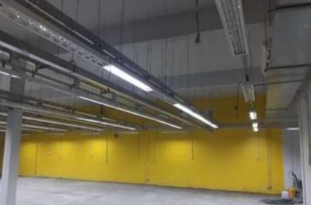 Galpão com parede amarela, tubulações e luminárias lineares
