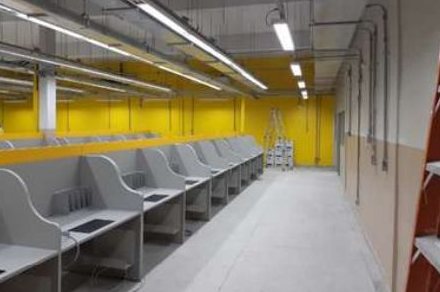 Corredor com bancadas de trabalho e instalações aparentes