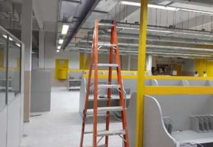 Ambiente em obra, com escada laranja e pilar amarelo