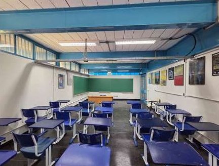 Sala de aula com quadro verde, carteiras azuis e forro novo