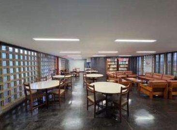 Sala de convivência reformada, com mesas e parede de cobogós